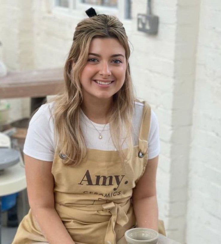 Amy Ceramics logosu baskılı camel önlük giyen kadın
