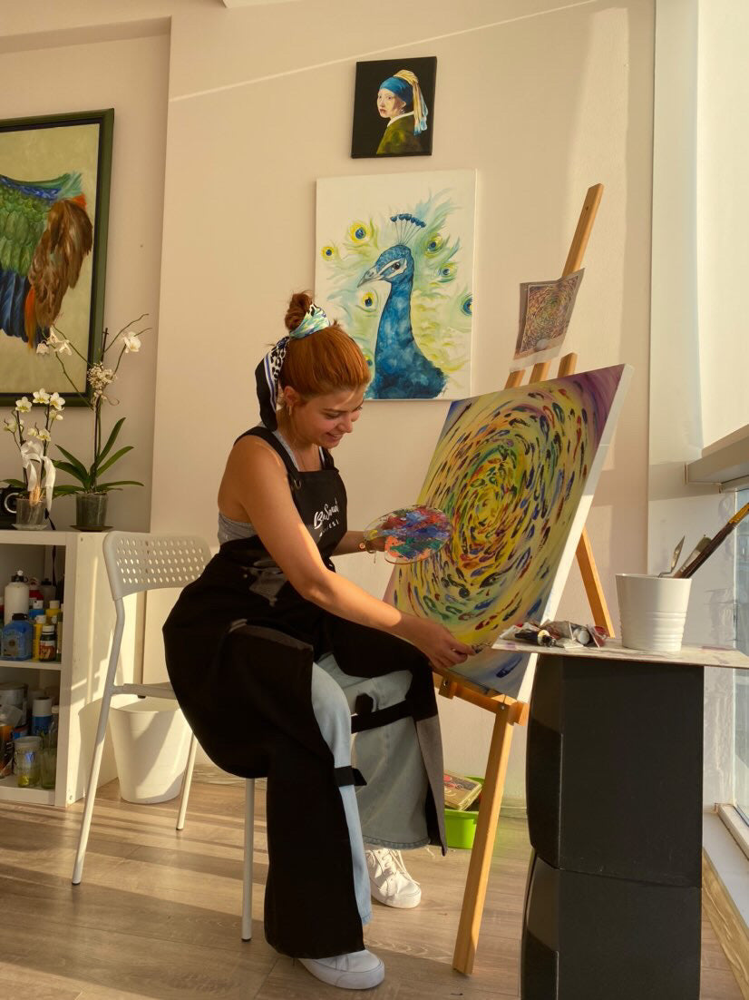 Siyah Hhopes önlüğüyle tuval üzerine resim yapan ressam