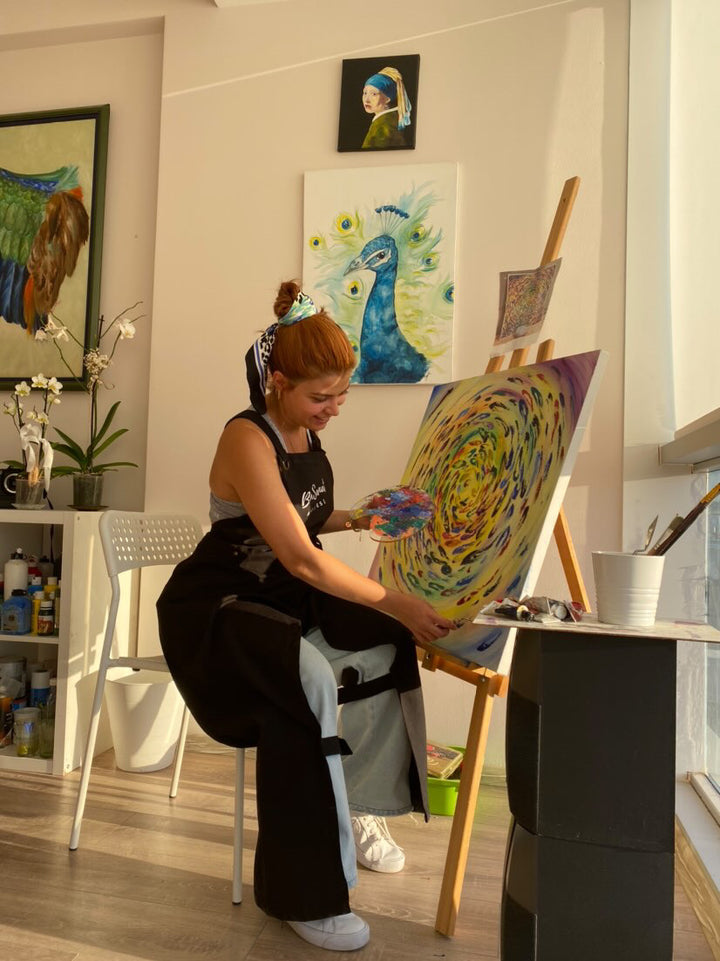 Siyah Hhopes önlüğüyle tuval üzerine resim yapan ressam