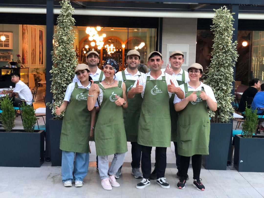 Kafe önünde logo baskılı yeşil önlükler giyen ekip